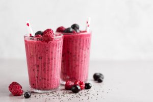 Tasty healthy dieting red berry smoothie with chia seeds in glasses on grey background. Closeup with copy space.